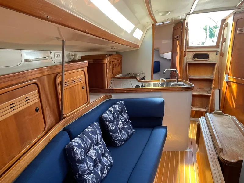 Slide: The Image of Interior of a 2001 C&C 110 sailboat with wooden cabinetry and blue seating. - 16