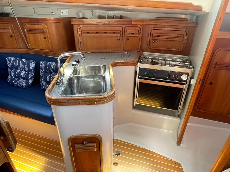 Slide: The Image of Compact kitchen area in a 2001 C&C 110 sailboat with sink, stove, and wooden cabinets. - 17
