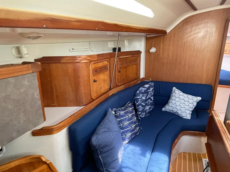 Slide: The Image of Interior of 2001 C&C 110 sailboat with blue cushioned seating and wooden cabinetry. - 19