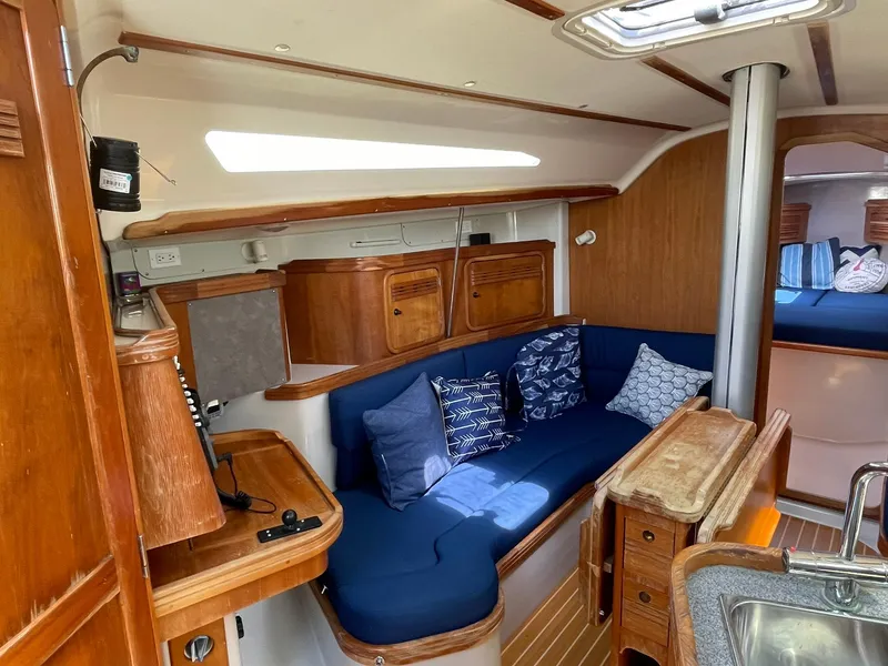 Slide: The Image of Interior of a 2001 C&C 110 sailboat with wooden cabinetry and blue seating. - 21