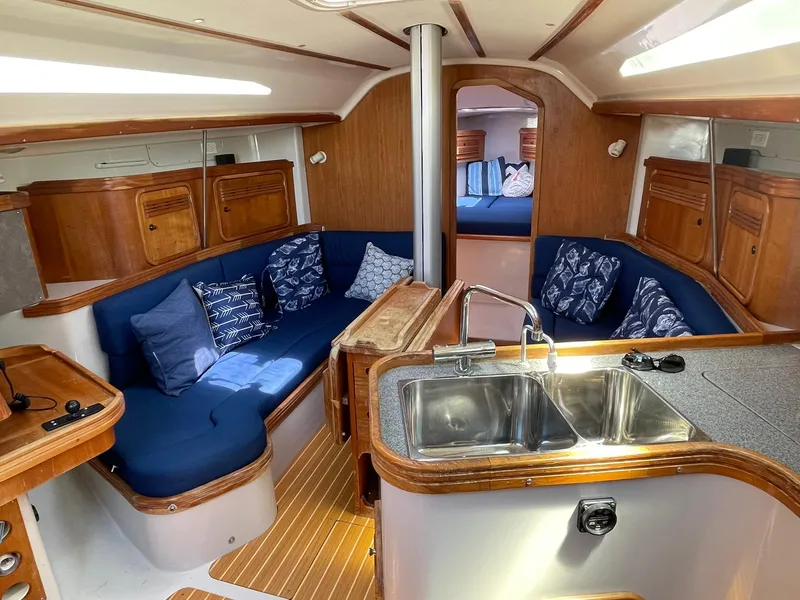 Slide: The Image of Interior of 2001 C&C 110 sailboat with blue seating, wooden cabinets, and kitchen sink. - 22