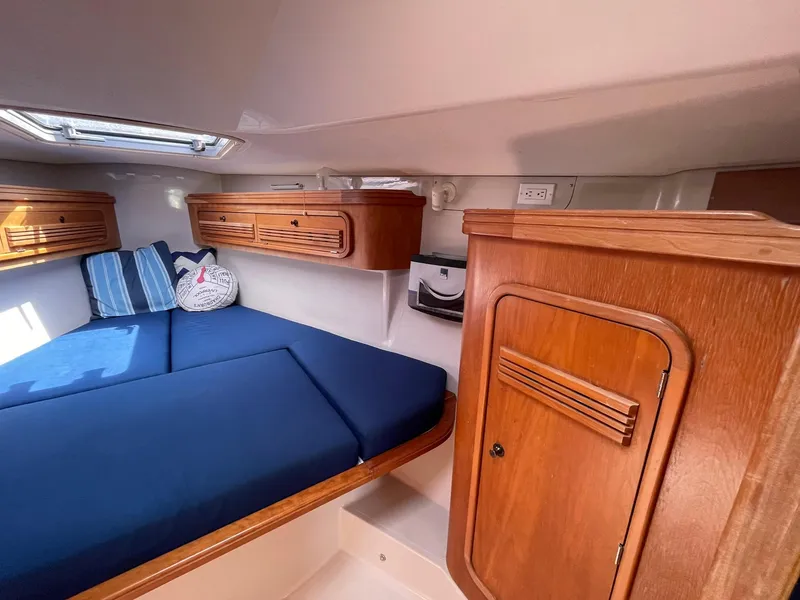 Slide: The Image of Cozy cabin interior of a 2001 C&C 110 sailboat with blue bedding and wooden storage. - 25
