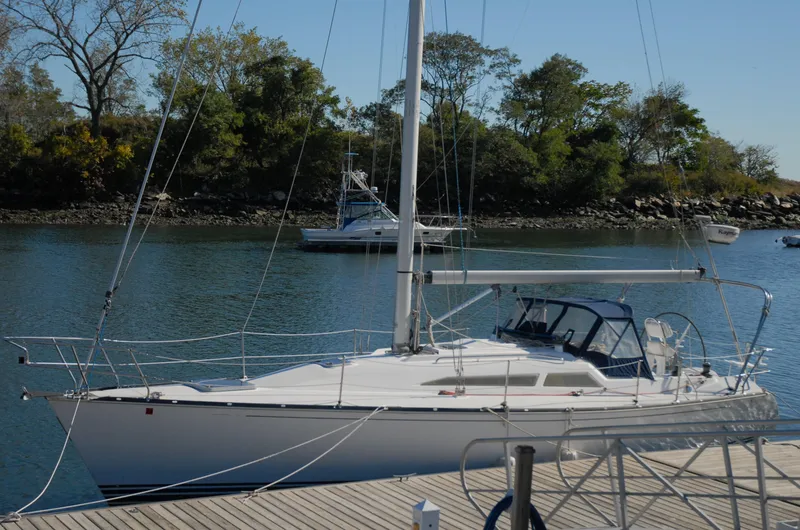 Slide: The Image of 2001 C&C 110 sailboat docked by a calm river with trees in the background. - 4