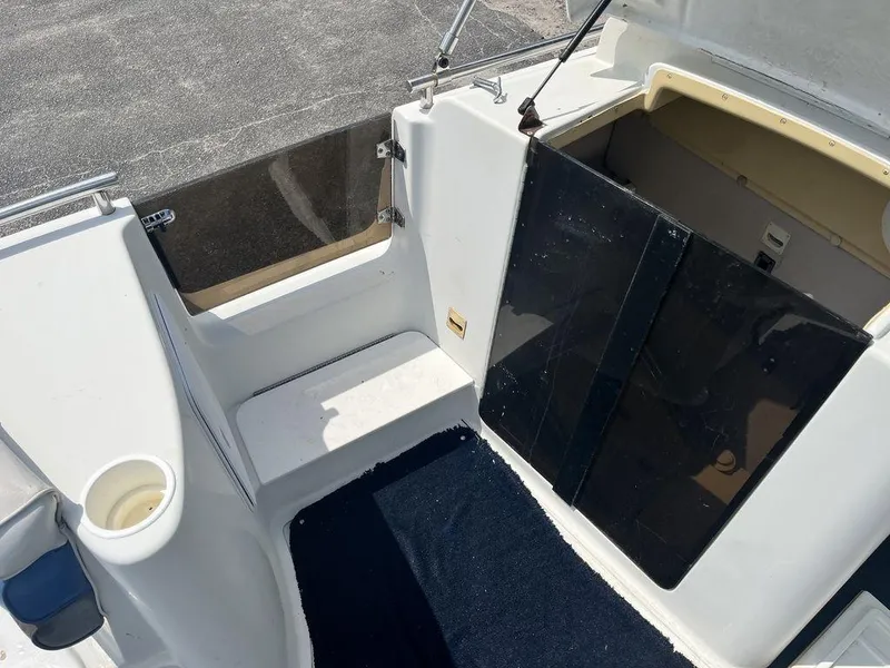 Slide: The Image of 1995 Hurricane FunDeck 240 boat interior with seating and cup holder, near grassy area. - 11