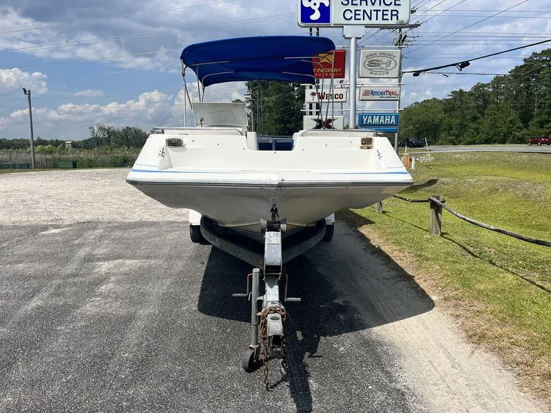 Slide: The Image of 1995 Hurricane FunDeck 240 boat on trailer with blue canopy under cloudy sky. - 2