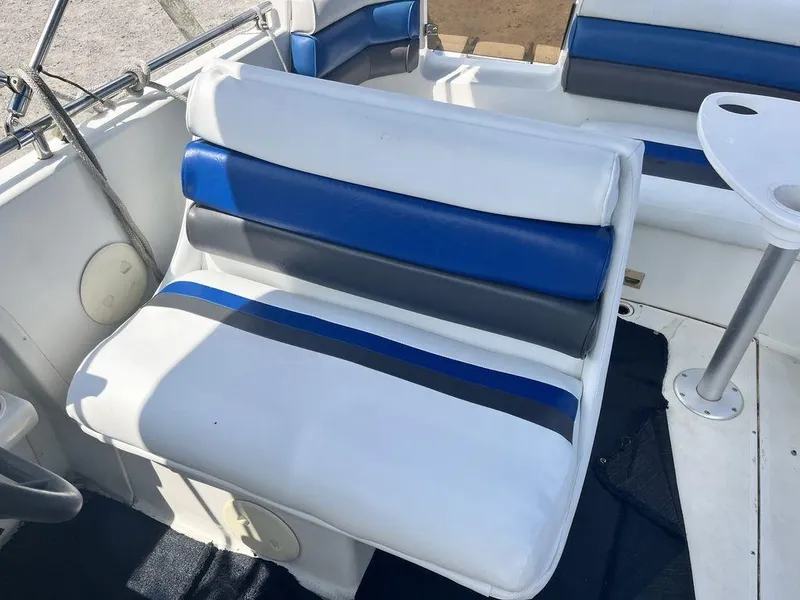 Slide: The Image of 1995 Hurricane FunDeck 240 boat on trailer, parked near dealership signs, under a blue sky. - 5