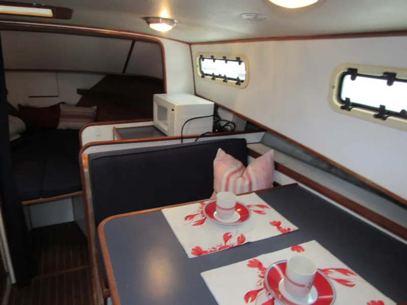 Slide: The Image of 1997 Norstar 302 boat interior with dining area, microwave, and cozy sleeping quarters. - 34