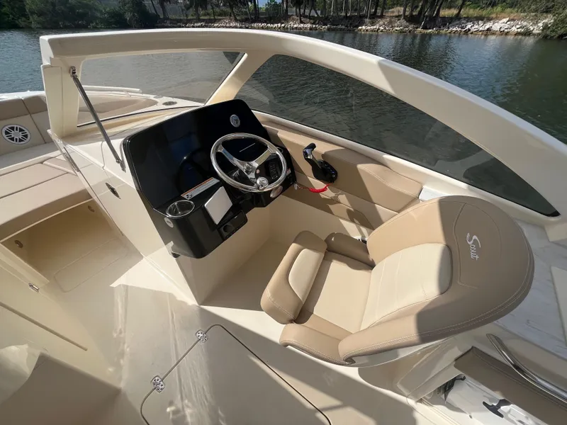 Slide: The Image of 2024 Scout 240 Dorado boat cockpit with steering wheel and beige seating. - 11