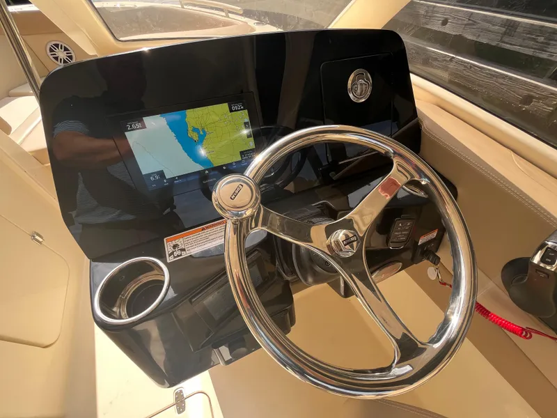 Slide: The Image of 2024 Scout 240 Dorado boat dashboard with steering wheel and navigation screen. - 13