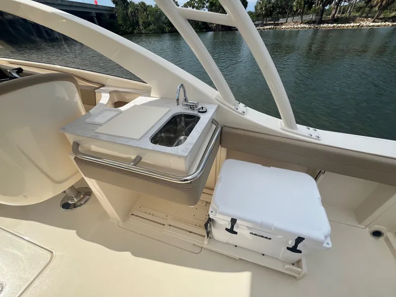 Slide: The Image of 2024 Scout 240 Dorado boat interior with sink and cooler by the water. - 15