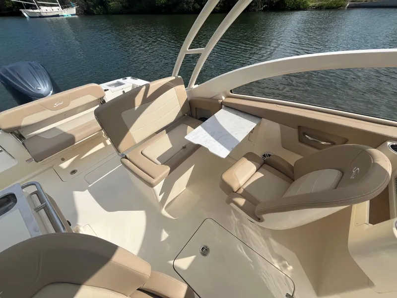 Slide: The Image of 2024 Scout 240 Dorado boat interior with beige seating and table on the water. - 18