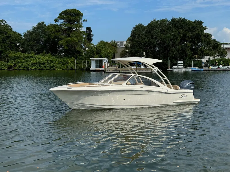 Slide: The Image of 2024 Scout 240 Dorado boat on a calm lake with trees in the background. - 2