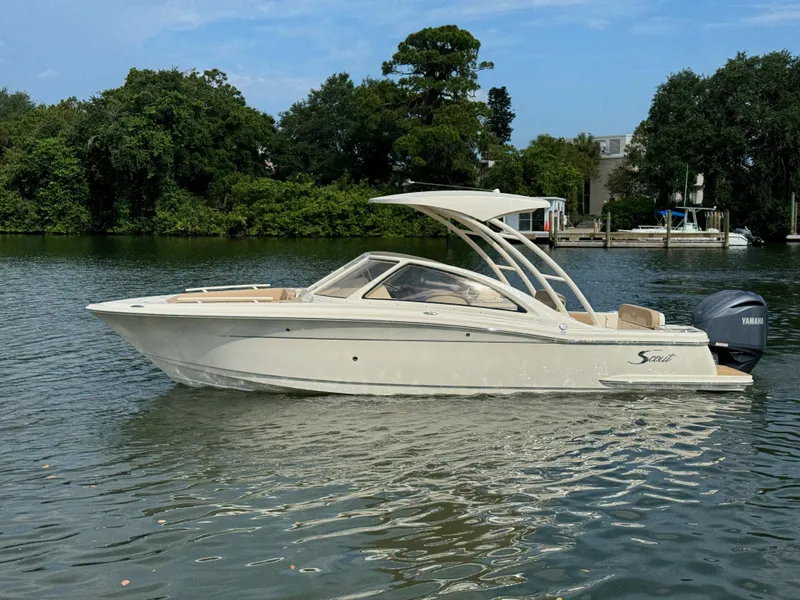 Slide: The Image of 2024 Scout 240 Dorado boat on calm water with lush green background. - 3