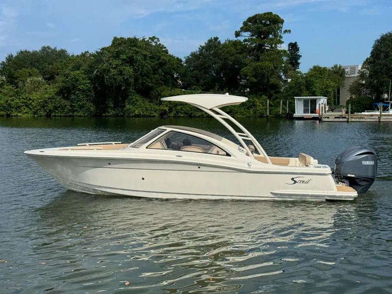 Slide: The Image of 2024 Scout 240 Dorado boat on calm water with lush greenery in the background. - 4