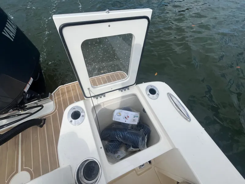 Slide: The Image of 2024 Scout 240 Dorado boat storage compartment with open lid, showing interior contents. - 7