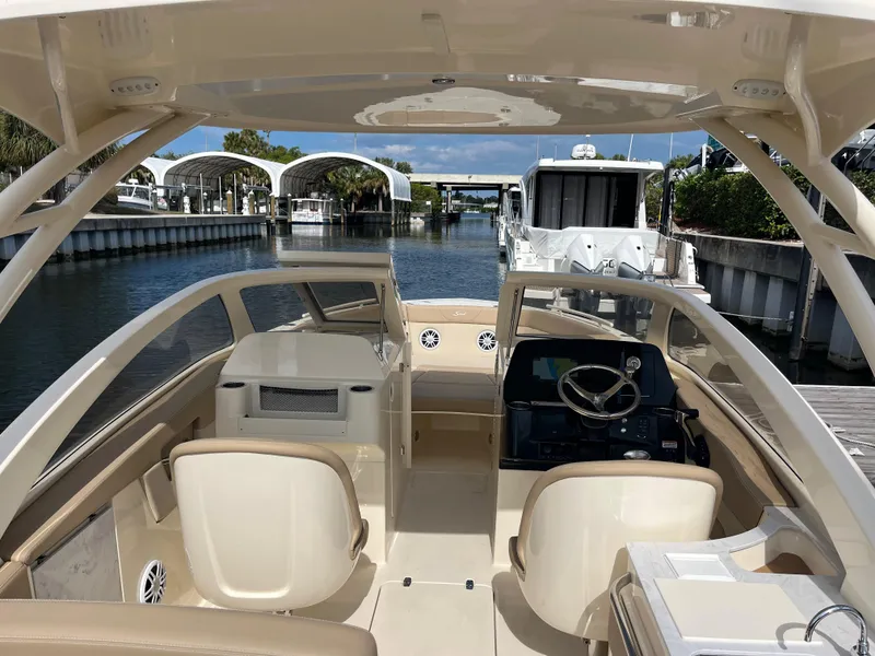 Slide: The Image of 2024 Scout 240 Dorado boat interior with helm and seating, docked in a marina. - 9