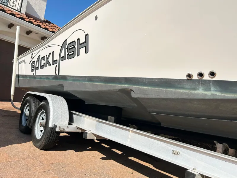 Slide: The Image of 2018 Tidewater 2700 Carolina Bay boat on trailer, side view with "Backlash" text. - 25