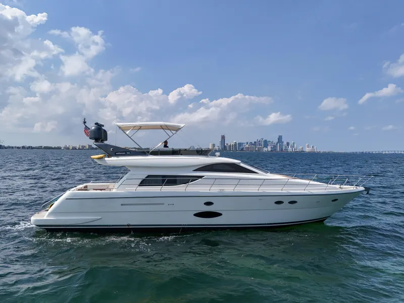 Slide: The Image of 2006 Uniesse 58 yacht cruising on open water with city skyline in the background. - 1