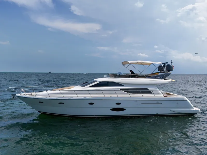 Slide: The Image of 2006 Uniesse 58 yacht cruising on open water under a clear sky. - 2