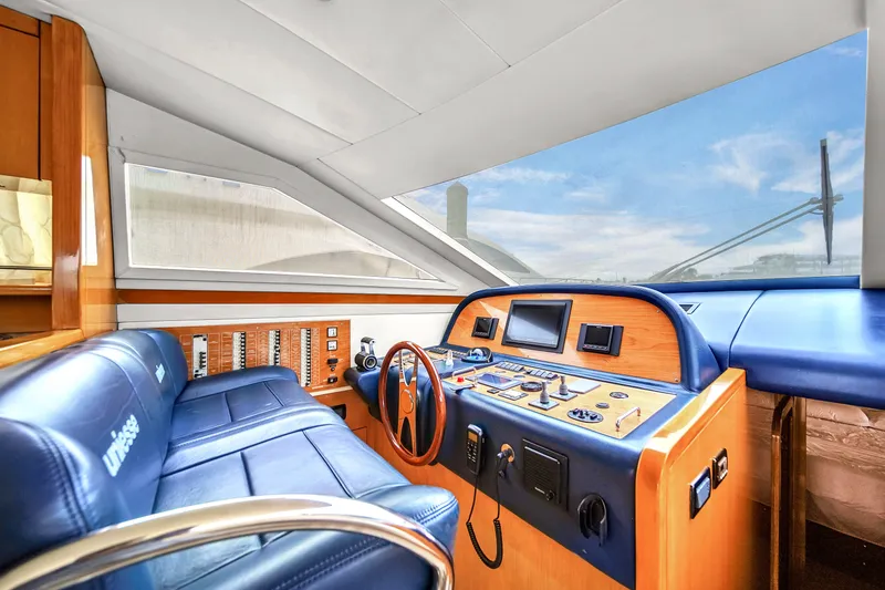 Slide: The Image of 2006 Uniesse 58 yacht helm with blue leather seats and modern navigation controls. - 23