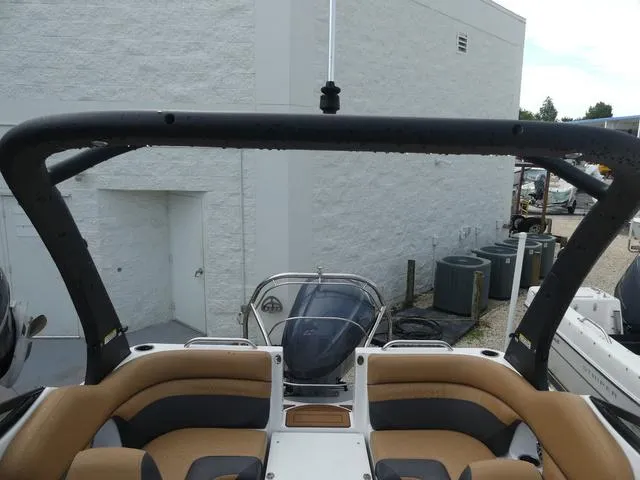 Slide: The Image of 2024 Hurricane SunDeck 2486 OB boat interior with tan and black seating, docked near a white building. - 22
