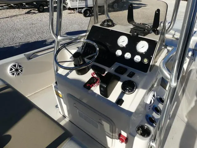 Slide: The Image of 2024 Bulls Bay 2200 boat console with steering wheel, gauges, and controls in a marina setting. - 6