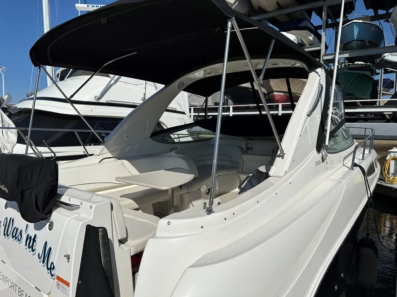 Slide: The Image of 2012 Bayliner 335 Cruiser docked at marina, featuring spacious seating and black canopy. - 3
