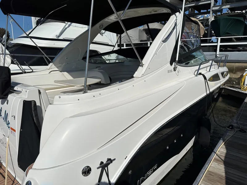 Slide: The Image of 2012 Bayliner 335 Cruiser docked at a marina, featuring sleek white and black design. - 6