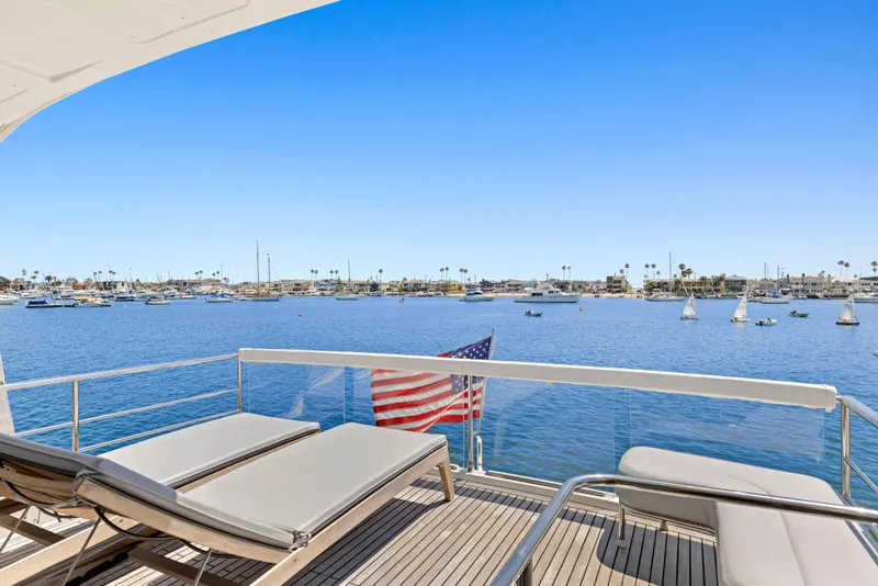 Slide: The Image of Luxury yacht deck view with sun loungers, overlooking a serene harbor. Absolute 64 FLY, 2015 model. - 24