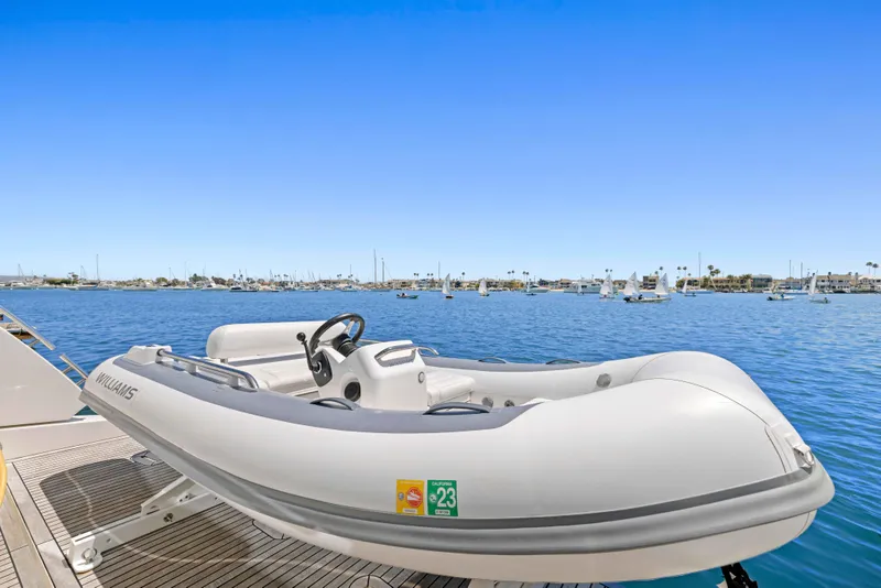 Slide: The Image of A white inflatable boat docked on a yacht, with a clear blue sky and calm sea. - 26