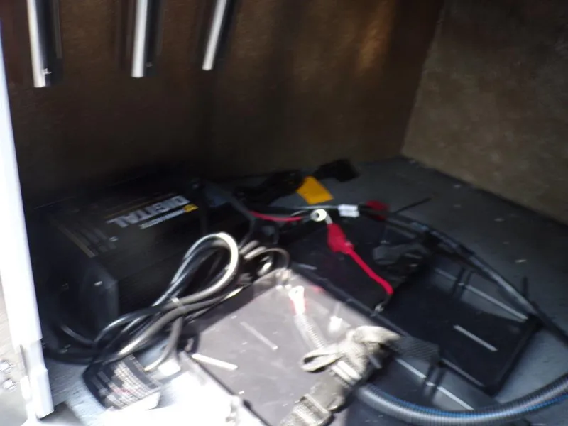 Slide: The Image of 2024 Xpress H190Bay boat storage compartment with battery charger and cables. - 11