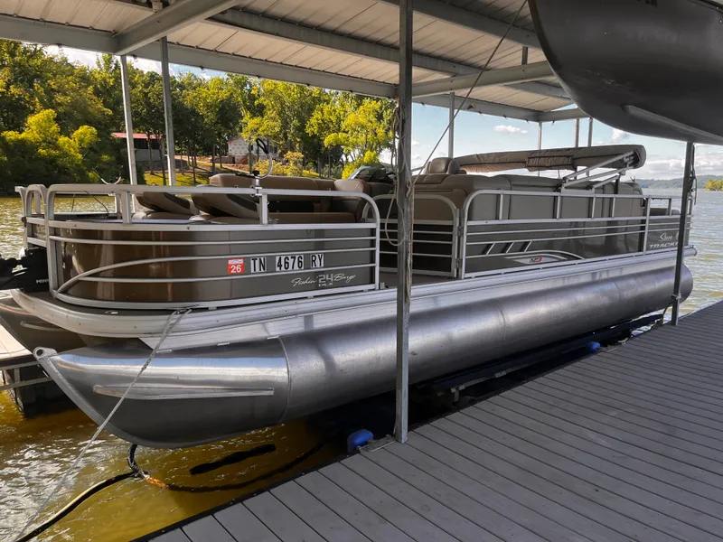 Slide: The Image of 2019 Sun Tracker Fishin' Barge 24 DLX pontoon boat docked under a covered slip. - 19