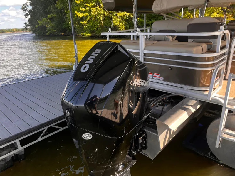 Slide: The Image of 2019 Sun Tracker Fishin' Barge 24 DLX with Mercury 250 outboard motor docked by a lake. - 23