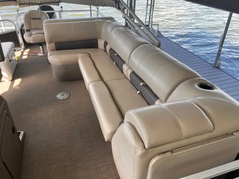 Slide: The Image of 2019 Sun Tracker Fishin' Barge 24 DLX interior with beige seating and lake view. - 29