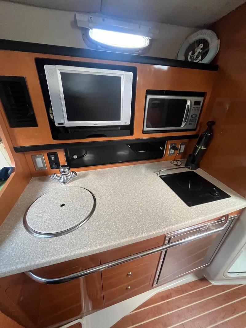 Slide: The Image of 2007 Chaparral Signature 280 galley with sink, stove, microwave, and TV. - 13
