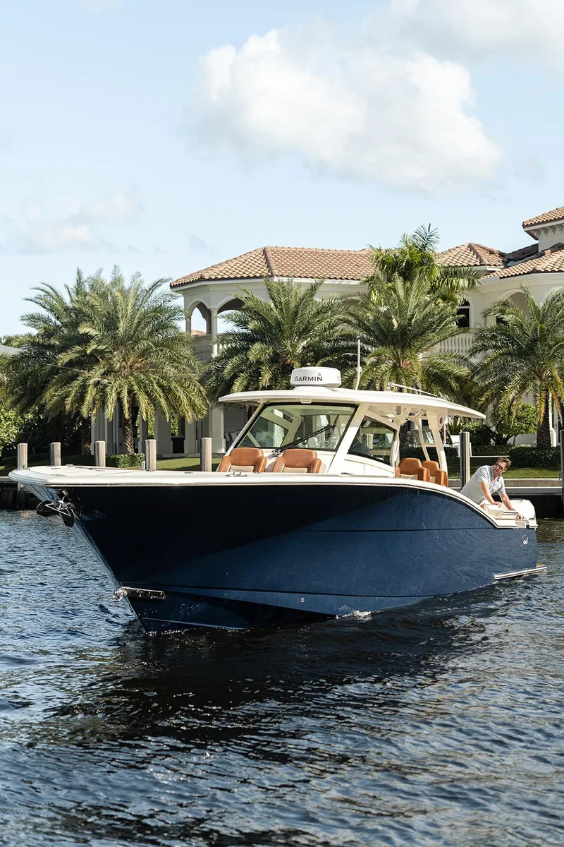 Slide: The Image of 2020 Scout 420 LXF boat cruising on a scenic waterway with palm trees. - 10