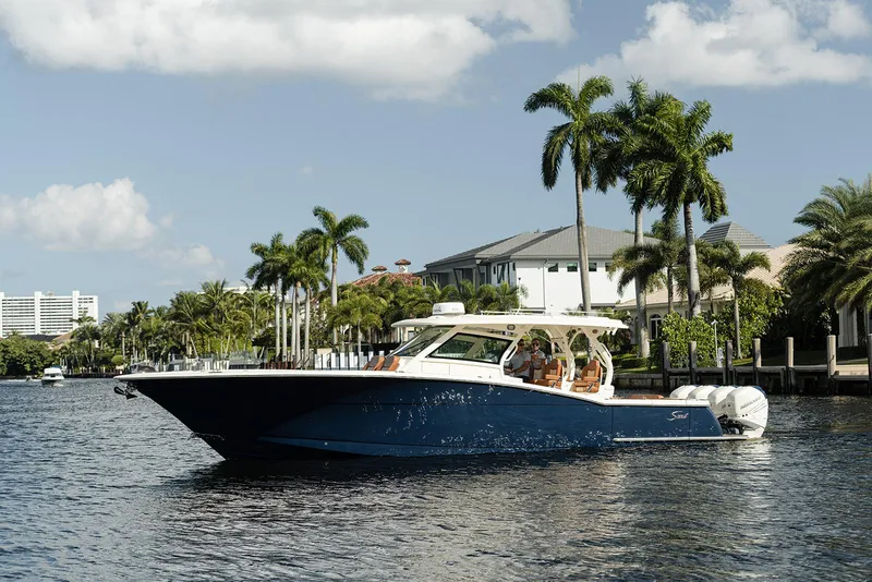 Slide: The Image of 2020 Scout 420 LXF boat cruising on a sunny day with palm trees in the background. - 3