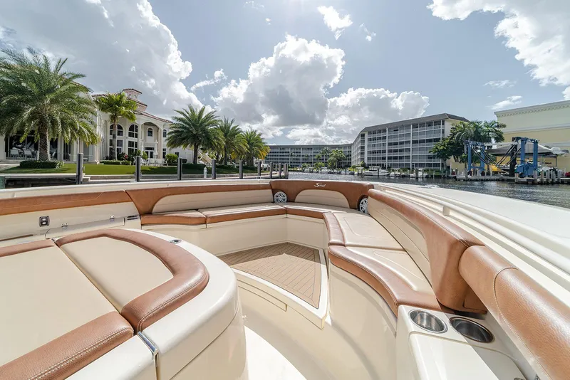 Slide: The Image of 2020 Scout 420 LXF boat interior with luxurious seating, docked near waterfront properties. - 31