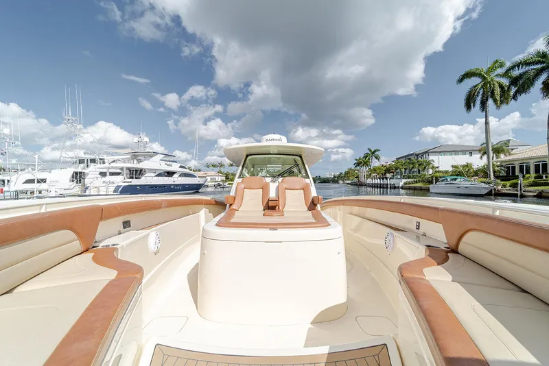 Slide: The Image of 2020 Scout 420 LXF luxury boat with tan seating, docked near palm trees and yachts. - 36
