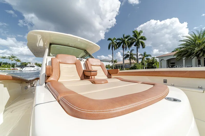 Slide: The Image of Luxurious seating on 2020 Scout 420 LXF boat with palm trees in background. - 39