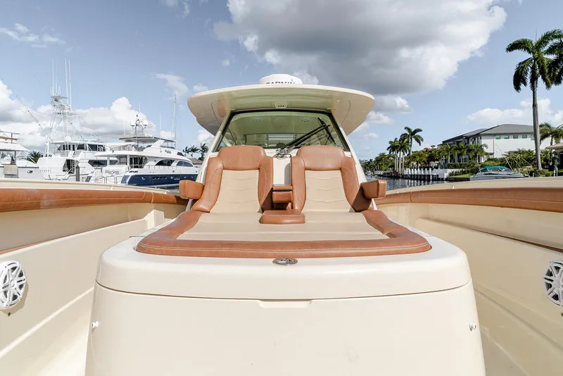 Slide: The Image of 2020 Scout 420 LXF luxury boat with tan seating, docked near palm trees and yachts. - 42