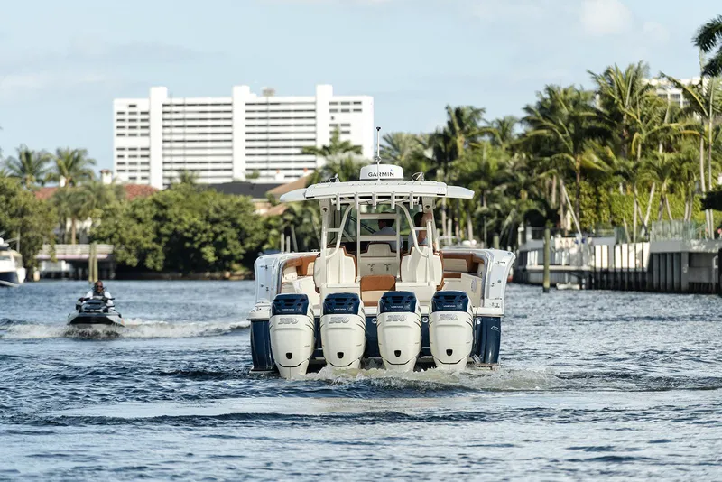 Slide: The Image of 2020 Scout 420 LXF boat cruising on a scenic waterway with palm trees and buildings. - 6