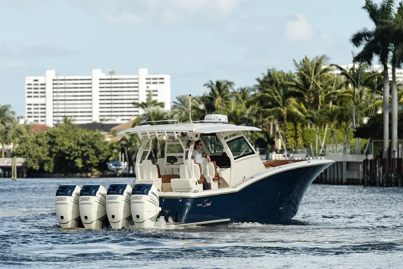 Slide: The Image of 2020 Scout 420 LXF boat cruising on a sunny day with palm trees in the background. - 7