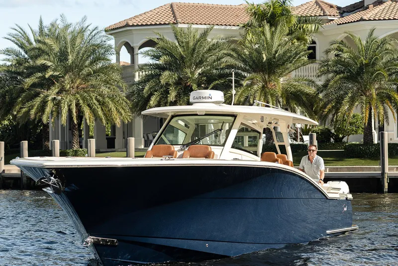 Slide: The Image of 2020 Scout 420 LXF boat cruising near waterfront mansion with palm trees. - 9