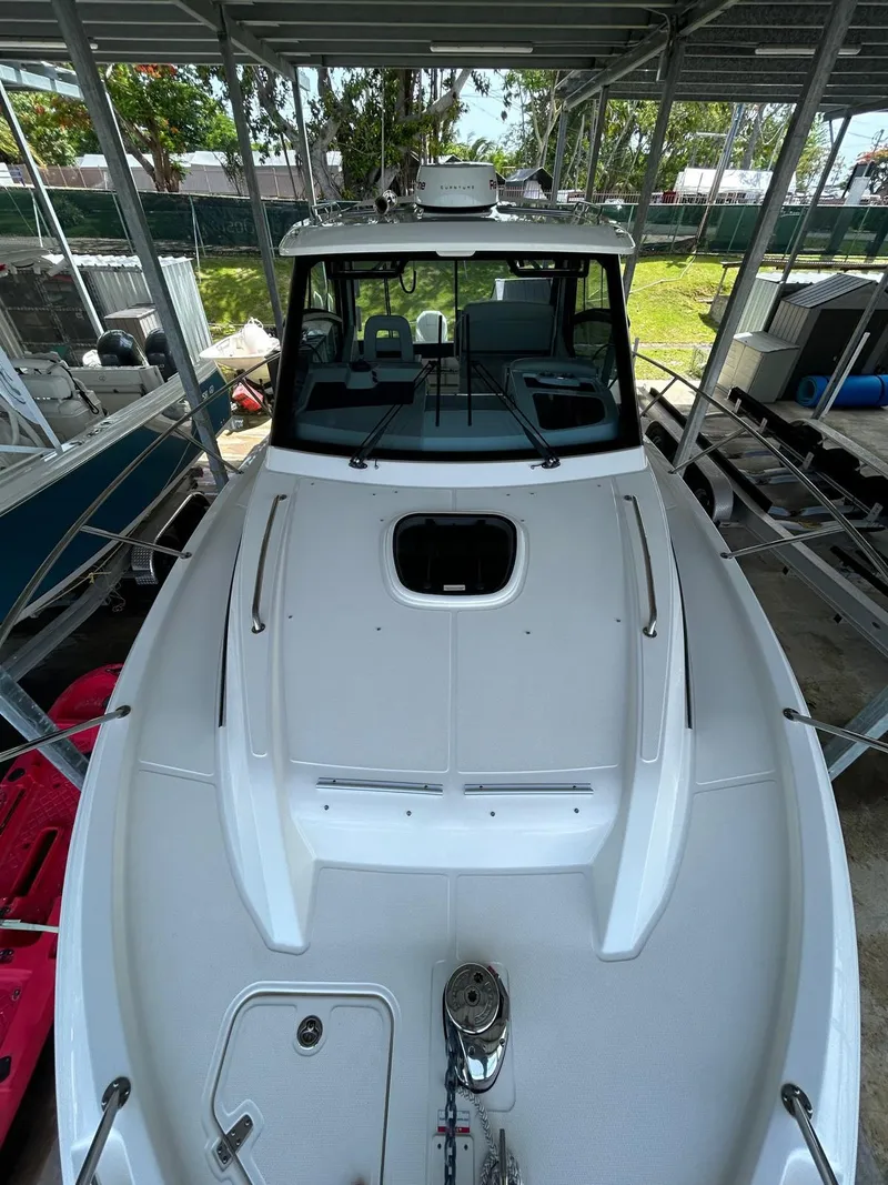 The Image of 2022 Boston Whaler 325 Conquest boat docked under a canopy. - 0