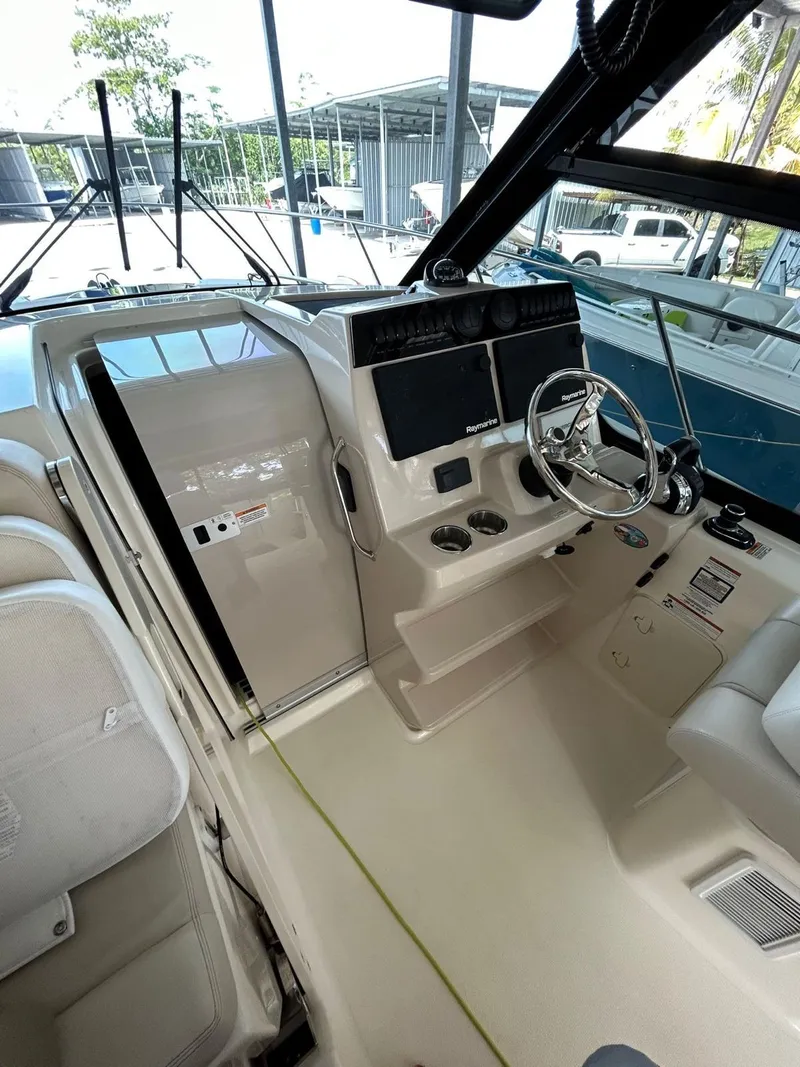 Slide: The Image of 2022 Boston Whaler 325 Conquest helm with modern controls and steering wheel. - 2