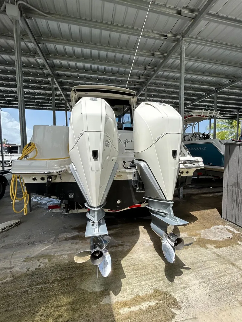 Slide: The Image of 2022 Boston Whaler 325 Conquest with dual outboard engines in a covered dock. - 7