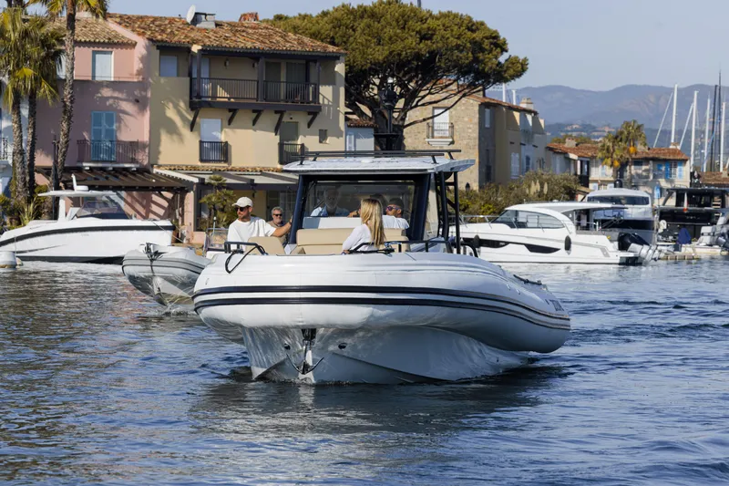 Slide: The Image of 2025 Zodiac X10CC boat cruising in a scenic waterfront area with houses and other boats. - 16