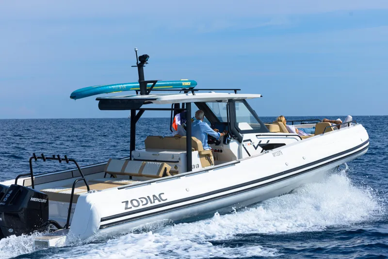 Slide: The Image of 2025 Zodiac X10CC boat cruising on open water with a paddleboard on top. - 22