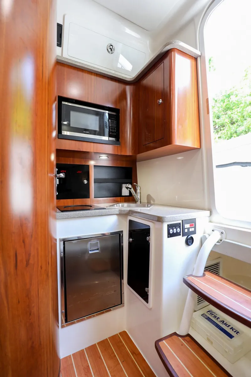 Slide: The Image of 2020 Regulator 41 boat interior kitchen with microwave and wooden cabinetry. - 27